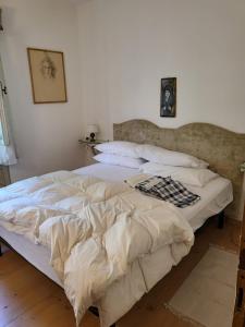 1 dormitorio con 1 cama grande con sábanas y almohadas blancas en Cortina, the place to be!, en Cortina dʼAmpezzo