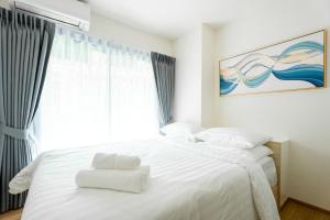 1 dormitorio con 1 cama blanca grande y ventana en Phyll Phuket 2 BR apartment near Central Festival by NLA, en Phuket