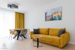 uma sala de estar com um sofá amarelo e uma mesa em Flatbook - City Center Apartments em Gdansk