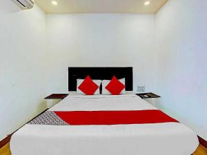 a bedroom with a large white bed with red pillows at Hotel O Meridian Grand in Shamshabad