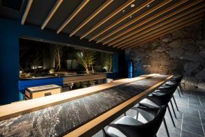 a bar with black chairs and a stone wall at Gekkoju Yufuin in Yufuin