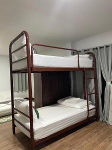 two bunk beds in a room with white sheets at Miggi's Home in Mae On