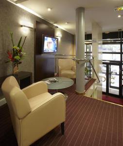 a waiting room with chairs and a table and a tv at Citadines République Paris in Paris