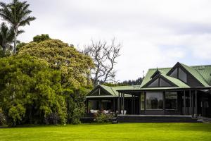 a black house with a green roof on a lawn at FOREST WATERS in Haruru