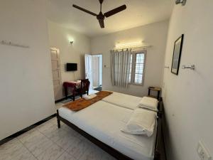 a bedroom with a large bed with a ceiling fan at Aambal Residency in Cochin