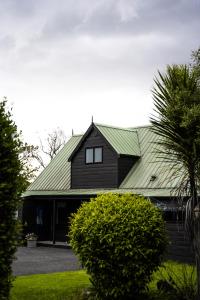 a black house with a green roof at FOREST WATERS in Haruru