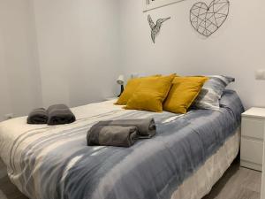 1 cama grande con almohadas amarillas y toallas. en Apartamento con encanto y piscina, en Fuengirola