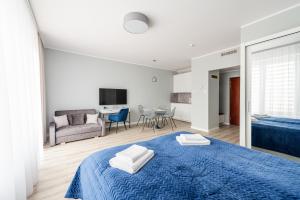 a bedroom with a blue bed and a living room at Apartamenty Sunline Kołobrzeg in Kołobrzeg