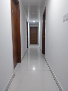 a corridor of a building with white floors and wooden doors at Royal Nest 4 BHK in Pune