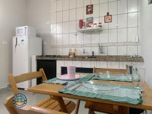 a kitchen with a wooden table and a refrigerator at Lindo Flat com Ar Perto do Mar in Caraguatatuba