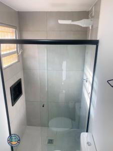 a shower with a glass door in a bathroom at Lindo Flat com Ar Perto do Mar in Caraguatatuba