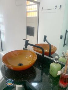 a bathroom with an orange sink and a mirror at Lindo Flat com Ar Perto do Mar in Caraguatatuba