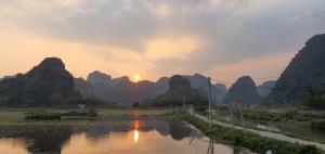 una puesta de sol sobre un río con montañas en el fondo en Ninh Binh Truong Nhan homestay en Ninh Binh