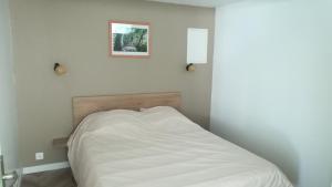 Una cama blanca en una habitación con una foto en la pared en Gîte de l'étang des sarcelles, en Saint-Martin-dʼAubigny
