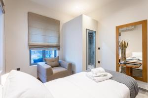una camera con un letto bianco e una sedia di Denthis Hotel - Taygetos Mountain Getaway a Artemisía