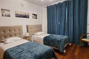a bedroom with two beds and blue curtains at Vista Mar Concórdia by Rentallido in Funchal