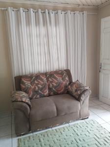eine braune Couch in einem Wohnzimmer neben einem Fenster in der Unterkunft RECANTO DA IZAURINHA in Olímpia