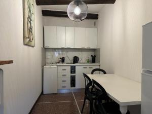 a kitchen with white cabinets and a table with chairs at Welc-oM Savonarola river view in Padova