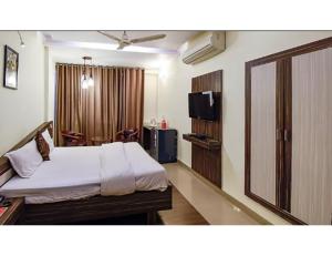 una camera d'albergo con letto e TV di Hotel Swayam, Jabalpur a Jabalpur