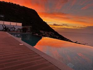 ein Pool am Meer bei Sonnenuntergang in der Unterkunft Villa Sea View in Arco da Calheta