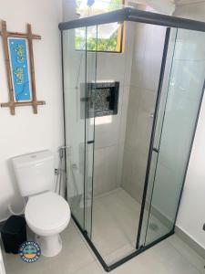 a bathroom with a glass shower with a toilet at Lindo Flat com Ar Perto do Mar in Caraguatatuba
