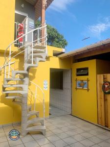 a spiral staircase on the side of a yellow building at Lindo Flat com Ar Perto do Mar in Caraguatatuba