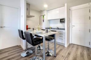 a kitchen with a table and black chairs at Apartamento Mirador - PlusHolidays in Calpe