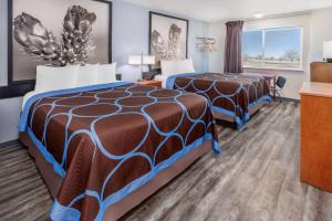a hotel room with two beds and a desk at Super 8 by Wyndham Clayton in Clayton