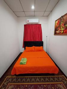 a bedroom with an orange bed with a red curtain at Fausal Legacy Homestay Sungai Besar in Sungai Besar