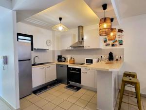 a kitchen with white cabinets and a black refrigerator at Le dodo bleu in Saint-Pierre