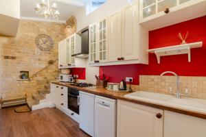 a kitchen with white cabinets and a red wall at Red Lion Cottage in Blockley