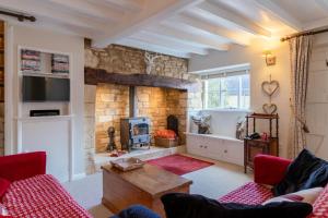 a living room with a fireplace and a stone wall at Red Lion Cottage in Blockley