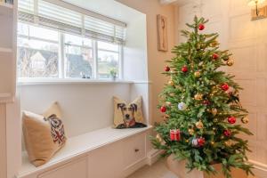 a christmas tree in a room with a dog on a window sill at Red Lion Cottage in Blockley