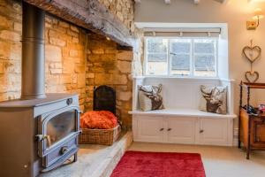 a kitchen with a stove and a brick wall at Red Lion Cottage in Blockley