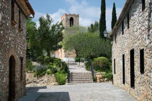 Une allée avec un bâtiment en pierre et une tour dans l'établissement Only Women Guest House - Villa de la Comunidad Internacional de la Mujer, à Olivella