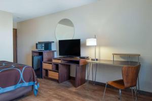 a bedroom with a bed and a desk with a television at Super 8 by Wyndham Livingston in Livingston