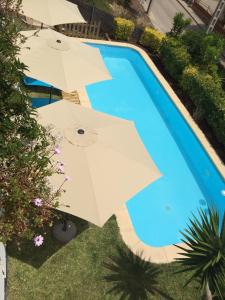 una vista panoramica su due ombrelloni accanto alla piscina di Only Women Guest House - Villa de la Comunidad Internacional de la Mujer a Olivella