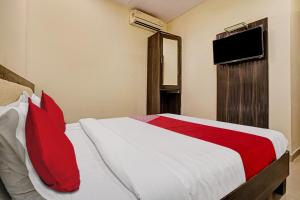 a bedroom with a bed with red pillows and a television at OYO Flagship Hotel Accore Inn in Mumbai