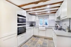 a kitchen with white cabinets and a wooden ceiling at Perfectly Presented Cottage Pass the Keys in Robertsbridge