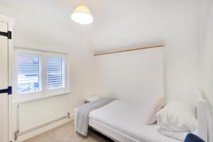 a white bedroom with a bed and a window at Perfectly Presented Cottage Pass the Keys in Robertsbridge