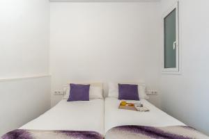 Cama blanca con almohadas moradas y ventana en AB Modern Gracia Apartment, en Barcelona