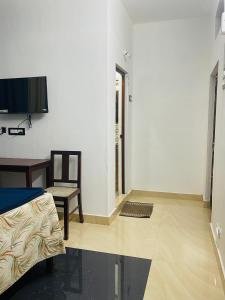a room with a bed and a tv and a chair at Puthookkadans Mareena Lodge in Kottayam