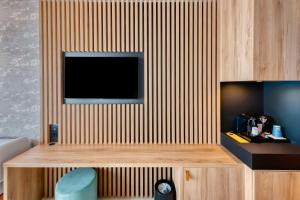 een kamer met een televisie aan een houten muur bij GOLDEN TULIP LYON OUEST TECHLID Hotel & Spa in Limonest