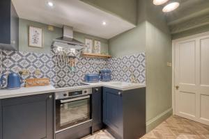 a kitchen with gray cabinets and a stove top oven at The Darwin Malvern Suite in Great Malvern