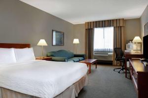 a hotel room with a bed and a couch and a desk at Days Inn by Wyndham Whitecourt in Whitecourt