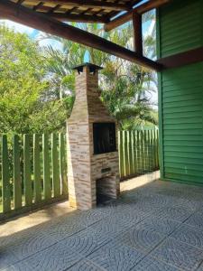 een stenen open haard op een patio naast een hek bij Chalé Carvalho - Verde in Itapoa