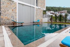 a swimming pool with two blue benches next to a building at Güllük Elegance Otel in Gulluk