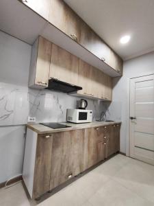 a kitchen with wooden cabinets and a microwave at Квартира посуточно in Kokshetau