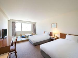 a hotel room with two beds and a desk at Mercure Urabandai Resort & Spa in Kitashiobara