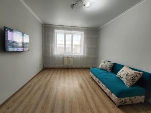 a living room with a blue couch and a window at Квартира посуточно in Kokshetau
